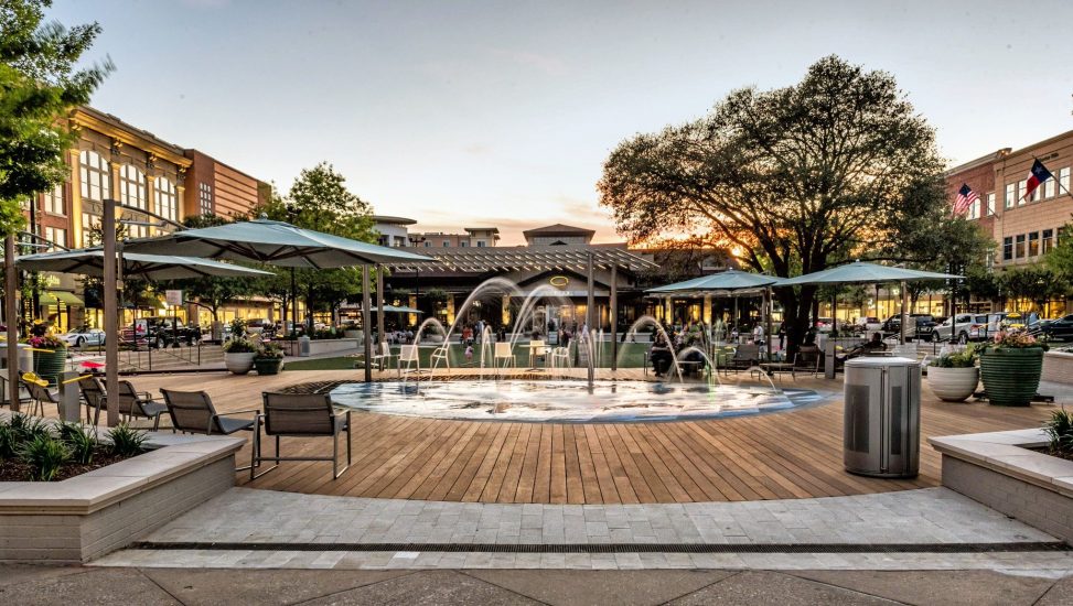 Interactive water feature and deck with vertical nozzles and arching spray jets at The Woodlands Market Street